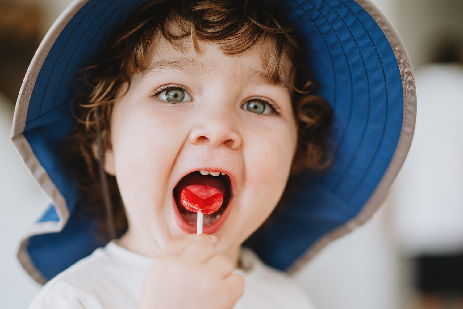 A picture of a kid eating a lolipop, wearing a Sunday Afternoons hat.
